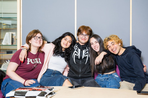 Ryhmä oppilaita hymyilee kameralle pöydän takana.