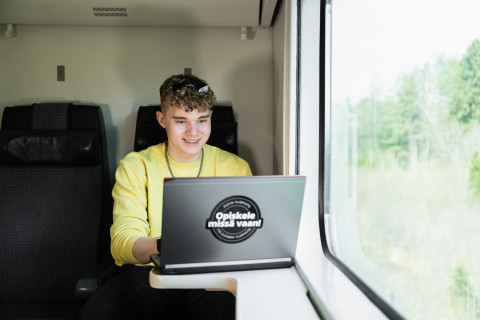 poika junassa opiskelee tietokoneella